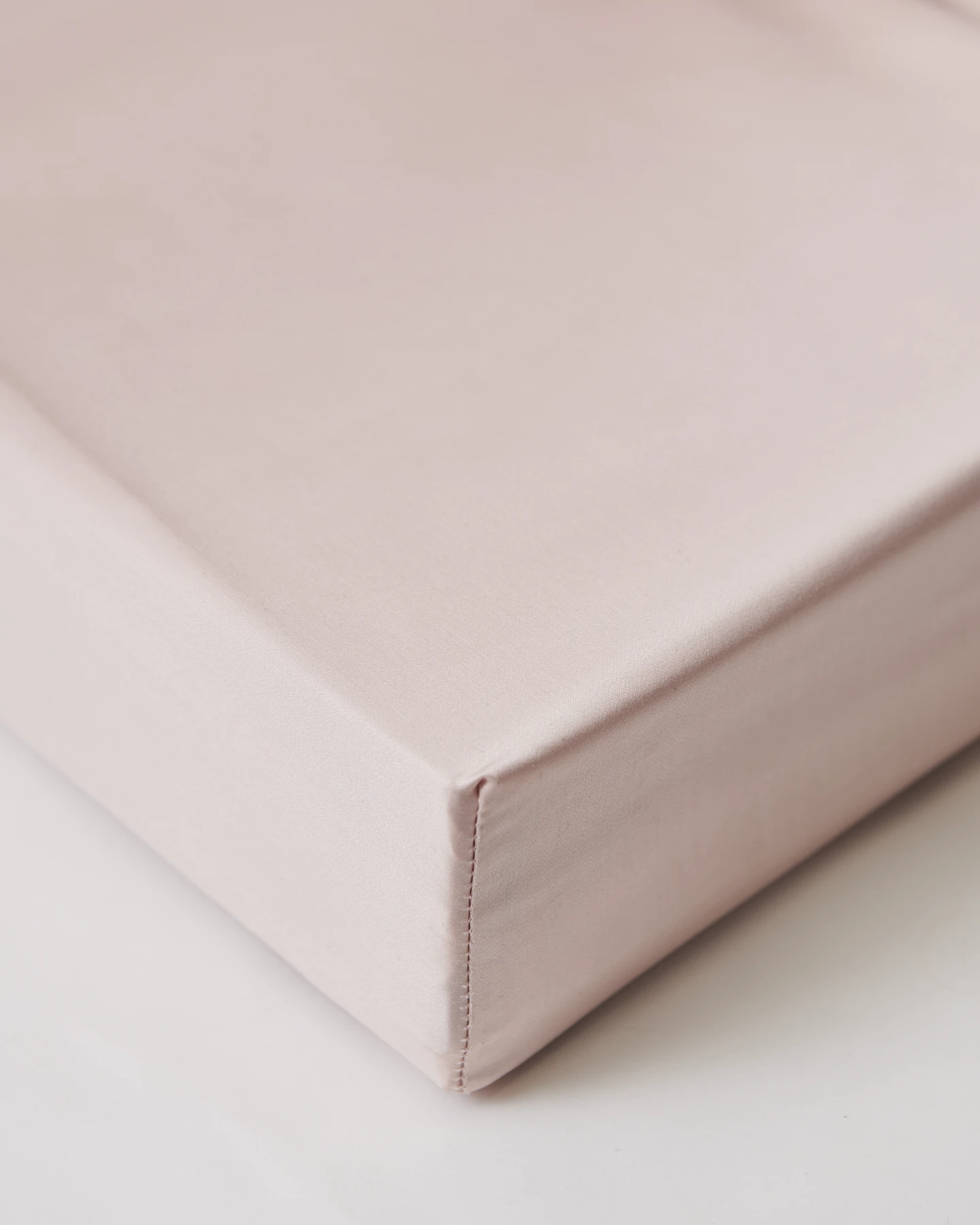 Fitted sheet Shade Dusty Pink i satin, kuvertsytt för perfekt passform. Tillverkat av ekologisk bomull. Ett mjukt och subtilt rosa lakan som adderar värme till sovrummet.